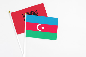 Azerbaijan and Albania stick flags on white background. High quality fabric, miniature national flag. Peaceful global concept.White floor for copy space.