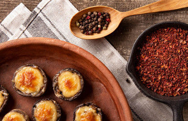 Roasted mushrooms with vegetables and parsley under melting cheese