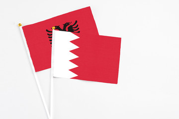 Bahrain and Albania stick flags on white background. High quality fabric, miniature national flag. Peaceful global concept.White floor for copy space.