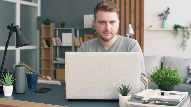Young man work with laptop in modern office. Freelancer in home office. Man typing on laptop keyboard. 4k slow motion footage.