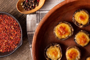 Roasted mushrooms with vegetables and parsley under melting cheese