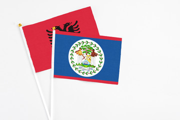 Belize and Albania stick flags on white background. High quality fabric, miniature national flag. Peaceful global concept.White floor for copy space.