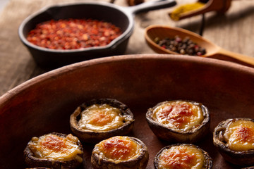 Roasted mushrooms with vegetables and parsley under melting cheese