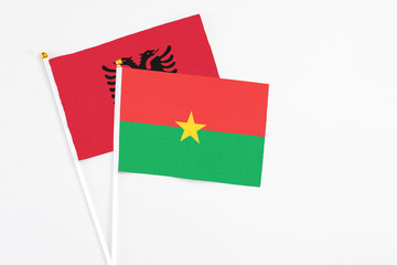 Burkina Faso and Albania stick flags on white background. High quality fabric, miniature national flag. Peaceful global concept.White floor for copy space.