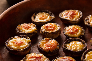 Roasted mushrooms with vegetables and parsley under melting cheese