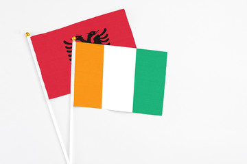 Fototapeta premium Cote D'Ivoire and Albania stick flags on white background. High quality fabric, miniature national flag. Peaceful global concept.White floor for copy space.