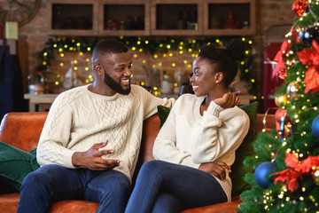 Obraz premium Romantic black couple sitting and chatting in decorated living room