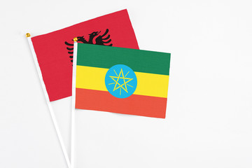 Ethiopia and Albania stick flags on white background. High quality fabric, miniature national flag. Peaceful global concept.White floor for copy space.