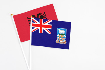 Fototapeta premium Falkland Islands and Albania stick flags on white background. High quality fabric, miniature national flag. Peaceful global concept.White floor for copy space.