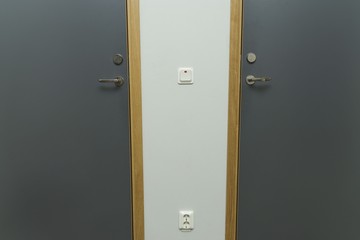 Close up view of power socket and power switch near door handle on wall and door. Interior design elements concept. 