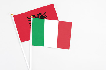 Italy and Albania stick flags on white background. High quality fabric, miniature national flag. Peaceful global concept.White floor for copy space.