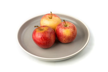 Plate of three whole ripe raw yellow and red apples