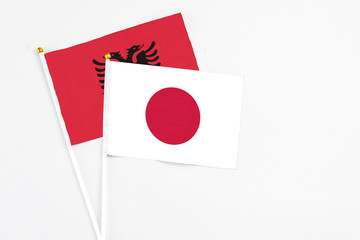 Japan and Albania stick flags on white background. High quality fabric, miniature national flag. Peaceful global concept.White floor for copy space.