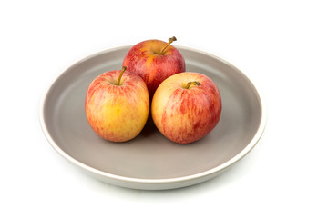 Plate of three whole ripe raw yellow and red apples