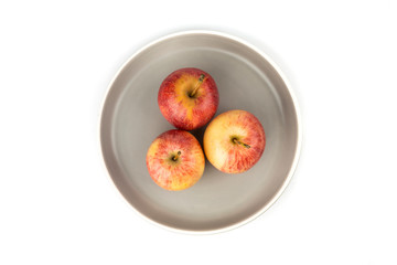 Plate of three whole ripe raw yellow and red apples