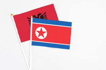 North Korea and Albania stick flags on white background. High quality fabric, miniature national flag. Peaceful global concept.White floor for copy space.