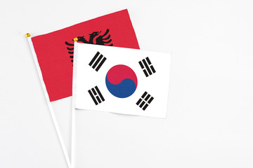 South Korea and Albania stick flags on white background. High quality fabric, miniature national flag. Peaceful global concept.White floor for copy space.