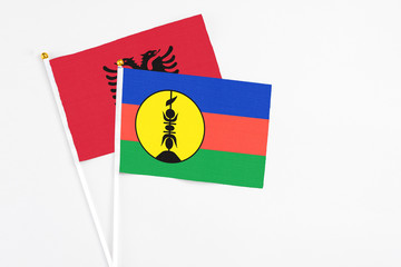 New Caledonia and Albania stick flags on white background. High quality fabric, miniature national flag. Peaceful global concept.White floor for copy space.