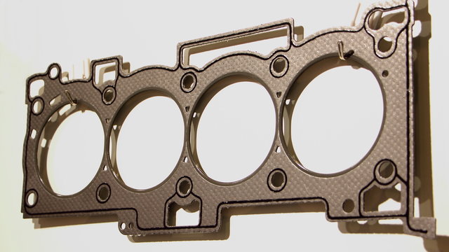 Closeup new engine cylinder head gasket with metal rings and sealing stripe, four cylinder car motor repair parts