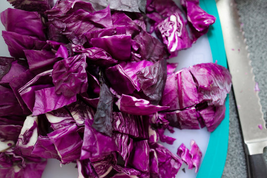Close-up of red cabbage chopped up on cutting board next to knife