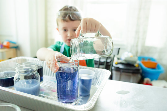 Elementary age boy pours water into a glass while doing a STEM project