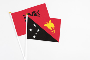 Papua New Guinea and Albania stick flags on white background. High quality fabric, miniature national flag. Peaceful global concept.White floor for copy space.