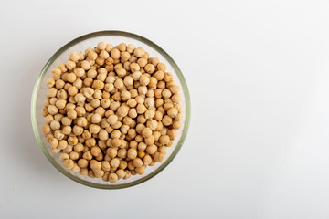 Dried chickpeas in a round glass plate on a white background