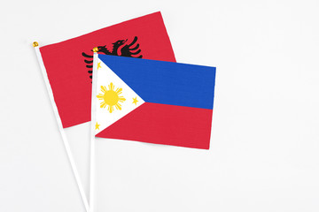 Philippines and Albania stick flags on white background. High quality fabric, miniature national flag. Peaceful global concept.White floor for copy space.