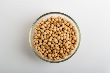 Dried chickpeas in a round glass plate on a white background