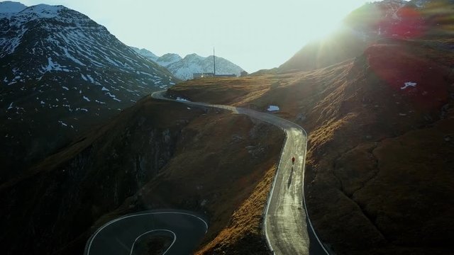 Road cyclist climbs up sunset mountain switchbacks