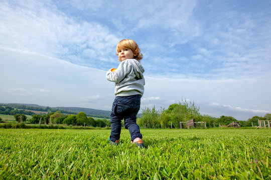 a little boy having fun on a green field in the country side, Caurel Brittany, France.