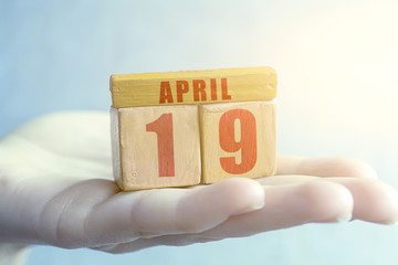 april 19th. Day 19 of month,Handmade wood cube with date month and day on female palm spring month, day of the year concept