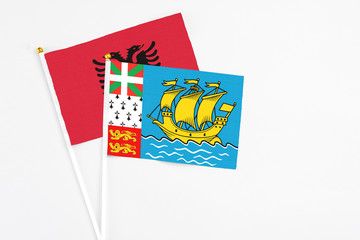 Obraz premium Saint Pierre And Miquelon and Albania stick flags on white background. High quality fabric, miniature national flag. Peaceful global concept.White floor for copy space.