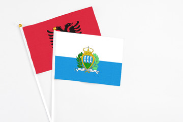 San Marino and Albania stick flags on white background. High quality fabric, miniature national flag. Peaceful global concept.White floor for copy space.