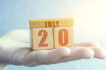 july 20th. Day 20 of month,Handmade wood cube with date month and day on female palm summer month, day of the year concept