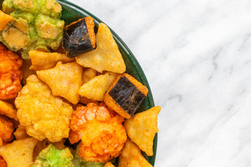 Japanese hot snacks with seaweed and wasabi lie in a green plate on a white marble surface