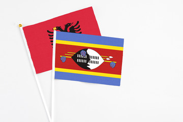 Swaziland and Albania stick flags on white background. High quality fabric, miniature national flag. Peaceful global concept.White floor for copy space.
