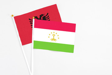 Tajikistan and Albania stick flags on white background. High quality fabric, miniature national flag. Peaceful global concept.White floor for copy space.