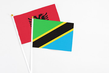 Tanzania and Albania stick flags on white background. High quality fabric, miniature national flag. Peaceful global concept.White floor for copy space.