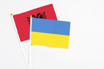Ukraine and Albania stick flags on white background. High quality fabric, miniature national flag. Peaceful global concept.White floor for copy space.