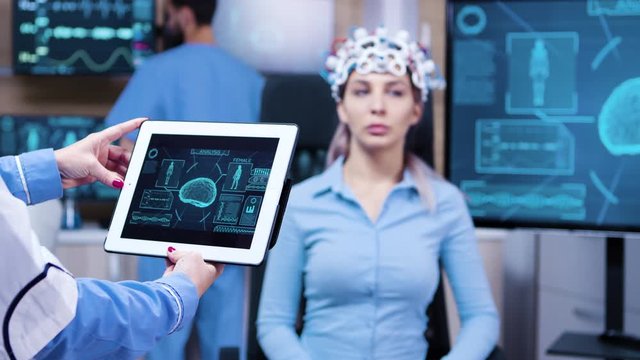 Female doctor looking at tablet with patient brain activty