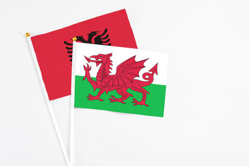 Wales and Albania stick flags on white background. High quality fabric, miniature national flag. Peaceful global concept.White floor for copy space.