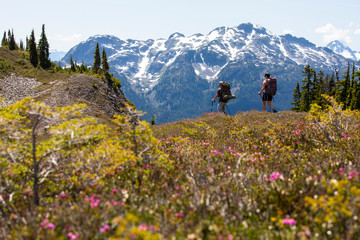 A couple hikes along a trail for a night of camping in the mountains.