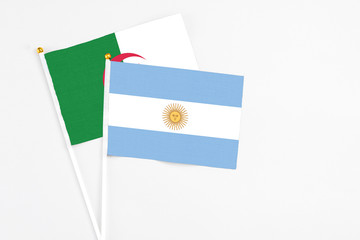 Argentina and Algeria stick flags on white background. High quality fabric, miniature national flag. Peaceful global concept.White floor for copy space.