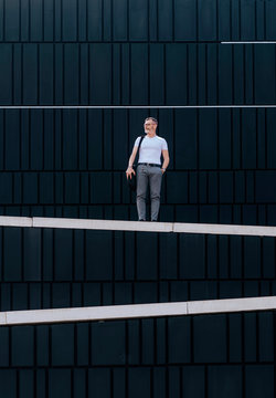 Adult bearded man with shoulder bag standing against wall in the city