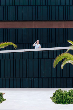 Mature bearded man using a mobile phone leaning on a fence