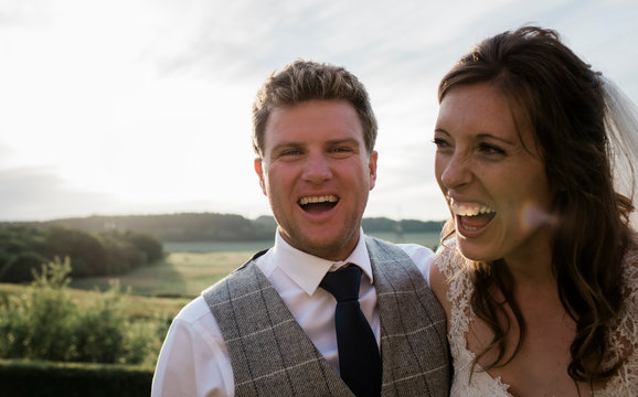 Newly married couple, bride and groom laughing on their wedding day