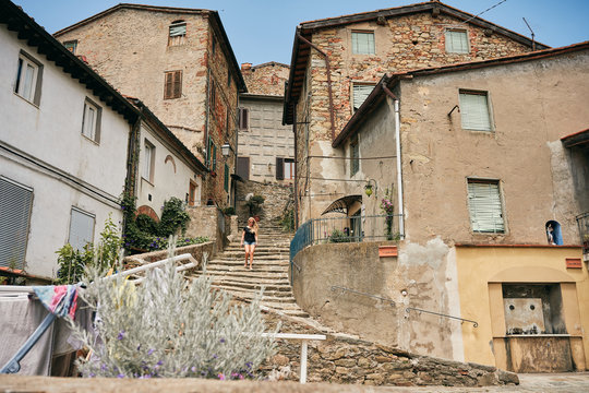 Woman walking downstairs on street by old buildings
