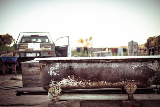 rusty freestanding outdoor tub sits by ute with fire wood on farm