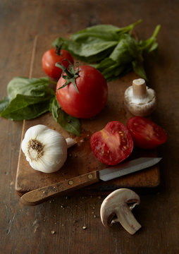 Tomatoes, basil, garlic and mushrooms on cutting board